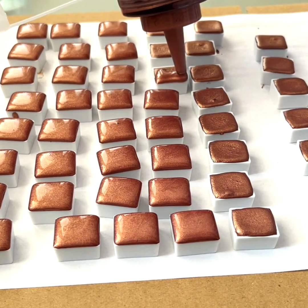 Grid of setting copper-bronze metallic watercolor half-pans during drying phase by VHacademy