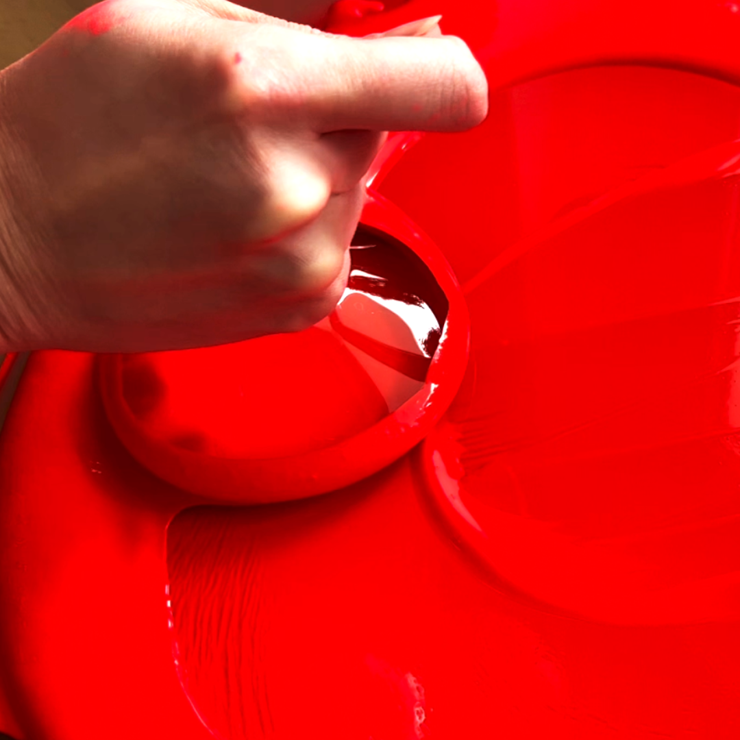 Close-up view of vibrant crimson red liquid pigment dispersion being hand-mixed by VHacademy