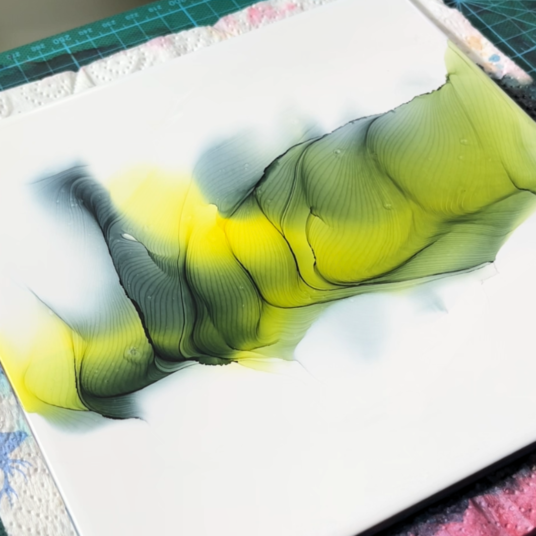 Centrally dispersed yellow and muted dark green alcohol ink showcasing fluid pooling and edge definition by VHacademy